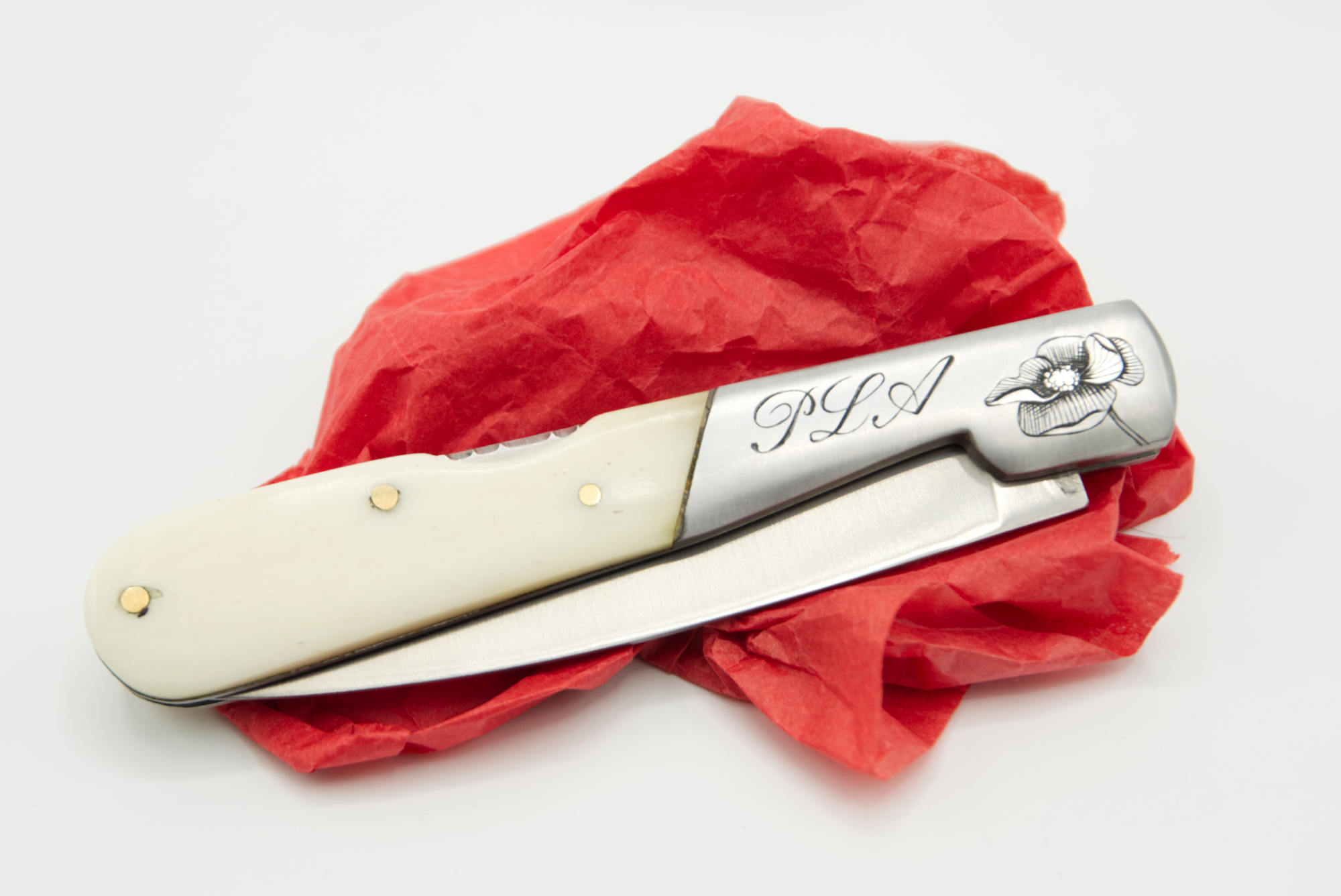 Gros plan sur les initiales et le motif Coquelicot gravés sur mitre de couteau inox